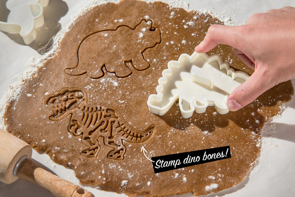 Man stamping out Dinosaur-shaped cookies.
